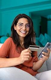 Woman on Couch with credit card and cell phone in hand